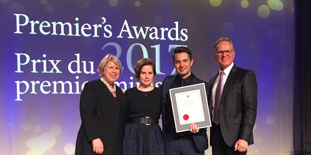 Brent Lessard receiving a Premier's award with Don Lovisa and others on a stage