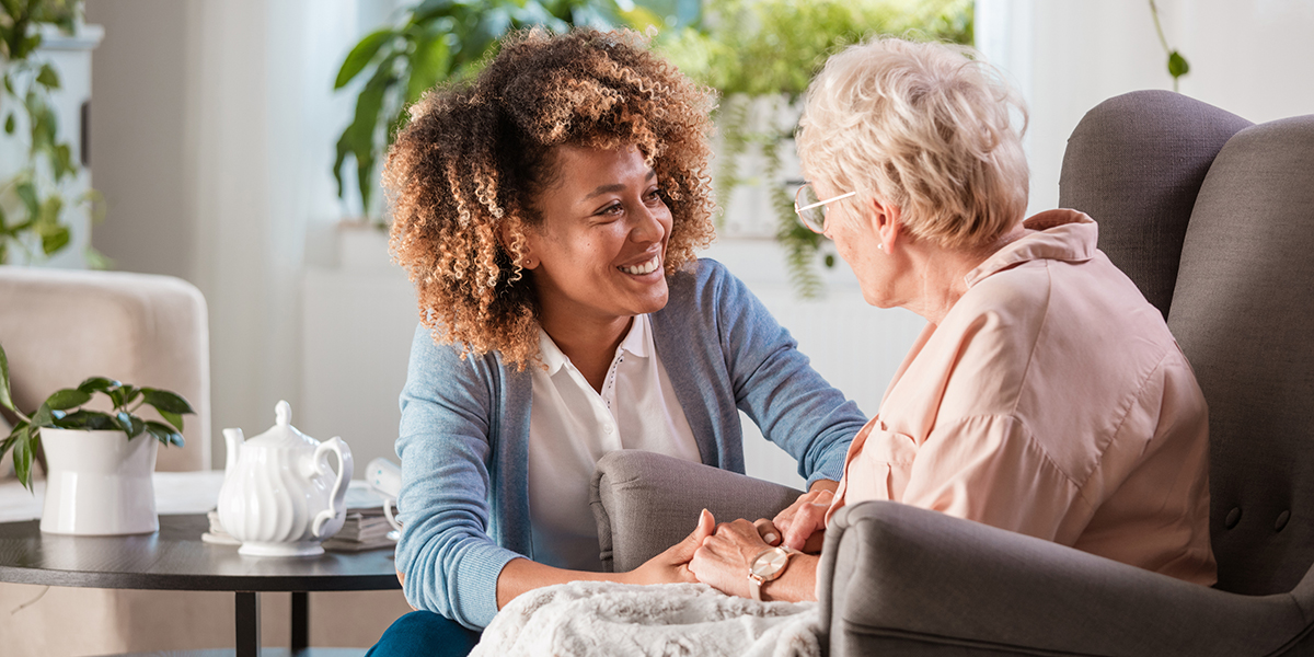 Lady talking to an elderly woman who is seated on a chair