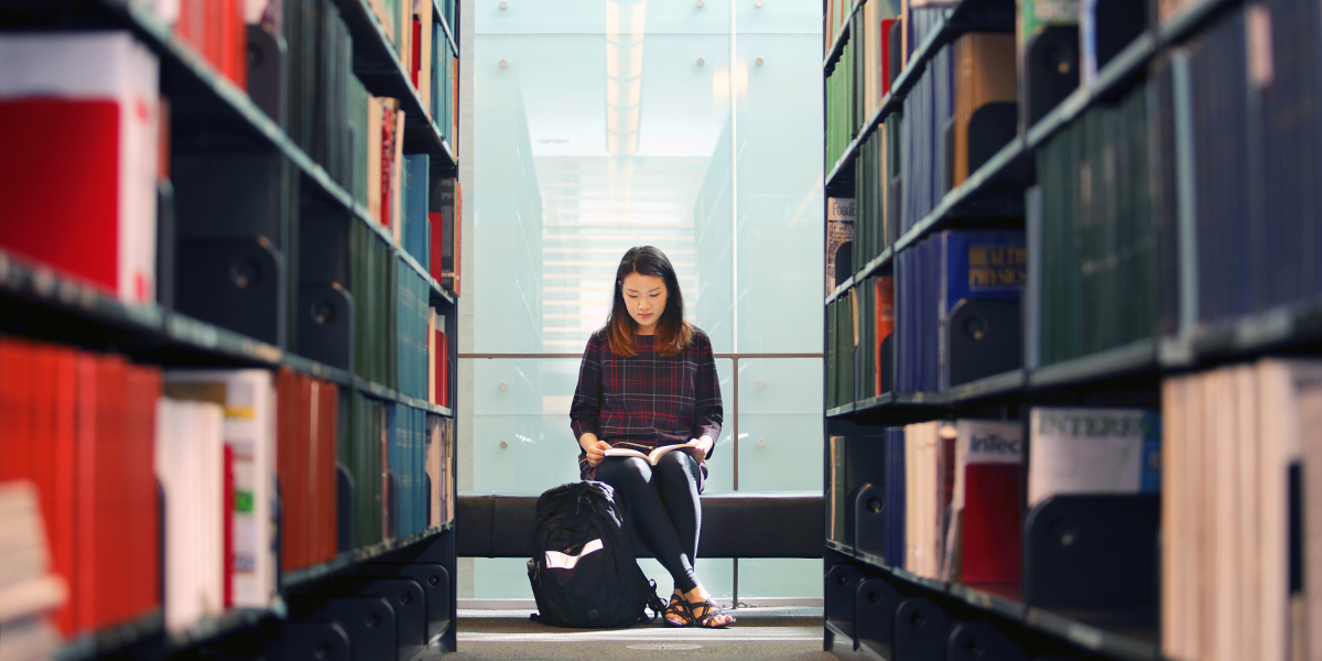 Female student reading a book in the library