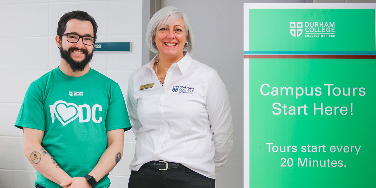 DC employees standing beside a campus tours sign at spring open house